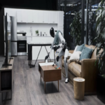Figure 03: El robot humanoide con apariencia realista que realiza tareas de limpieza y organización en el espacio habitable de forma autónoma.